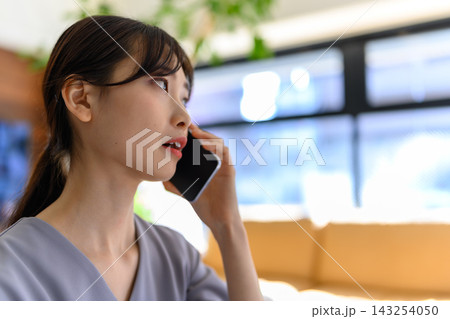 スマートフォンで通話しながら相談に乗る女性 スマートフォンで通話しながら相談に乗る女性 143254050