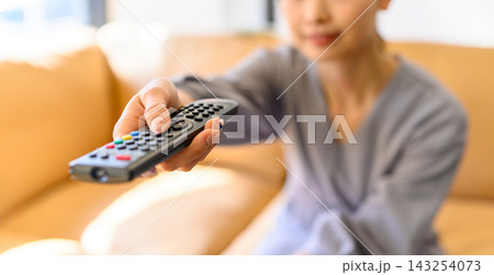 リモコンを操作してテレビを選ぶ女性の手元 143254073