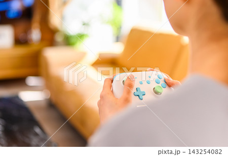 リビングでゲームコントローラーを持って遊ぶ女性 143254082