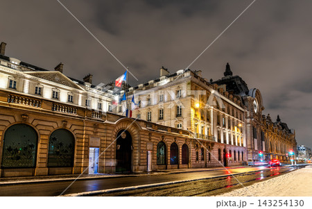 Illuminating night view of the historic Musee d'Orsay and French government buildings along the Seine river under a winter snowy sky in Paris, France. Illuminating night view of the historic Musee d'Orsay and French government buildings along the Seine river under a winter snowy sky in Paris, France. 143254130