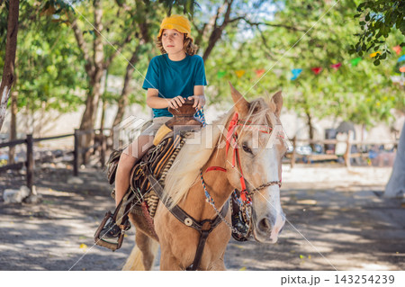Child rides a palomino horse during a family farm visit. Outdoor recreation and family farm leisure. Child rides a palomino horse during a family farm visit. Outdoor recreation and family farm leisure. 143254239