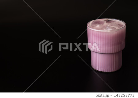 Ribbed pink glass filled with an iced berry drink stands against a deep black background. Premium beverage styling creates a refreshment concept Ribbed pink glass filled with an iced berry drink stands against a deep black background. Premium beverage styling creates a refreshment concept 143255773