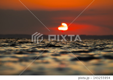 Sun setting over rippled water surface at dusk 143255954