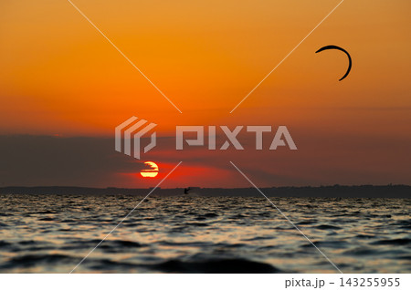 Kitesurfer silhouette during sunset over water Kitesurfer silhouette during sunset over water 143255955