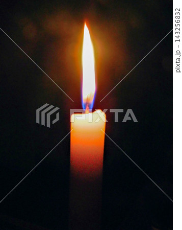 A candle brightly lit in a dark room yellow flame 143256832