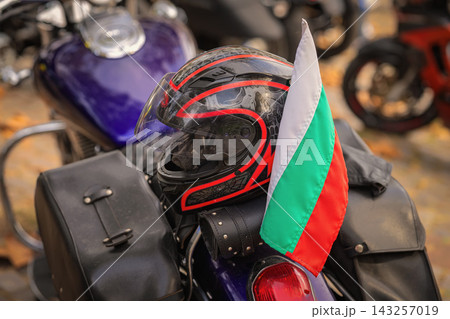Bulgarian Flag and Helmet on Parked Motorcycle Close-up. Parked touring bike outdoor, road spirit, adventure, patriotic race. Concept of biker culture, travel and Bulgarian identity 143257019