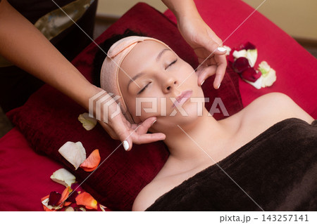 a masseuse in a cosmetology salon makes a Thai massage on the face of a young girl 143257141