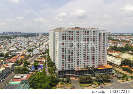 An elevated cityscape shows dense residential development with high-rise apartment buildings displaying numerous Vietnamese flags beneath a cloudy sky. 143257219