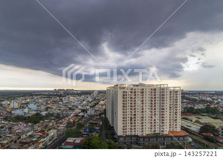 A panoramic elevated view shows dense residential buildings and rooftops beneath a vast sky filled with dark storm clouds. A panoramic elevated view shows dense residential buildings and rooftops beneath a vast sky filled with dark storm clouds. 143257221
