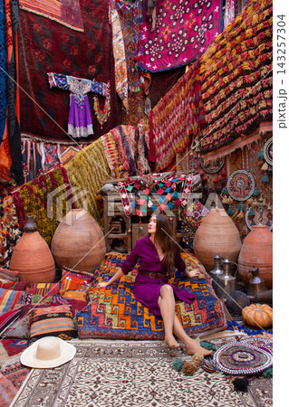 a beautiful girl in dress in a traditional turkish interior with many carpets on the wall a beautiful girl in dress in a traditional turkish interior with many carpets on the wall 143257304