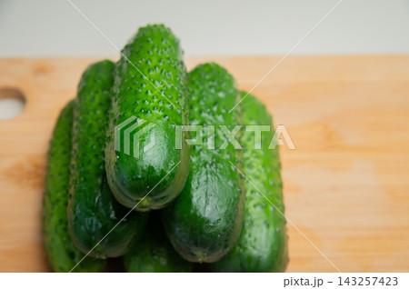 Fresh green cucumbers on wooden cutting board 143257423