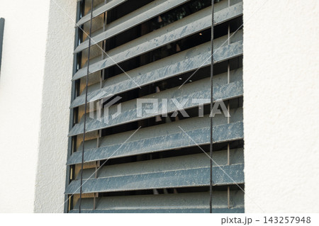Window shutters made of durable materials are installed on the exterior of a modern residential building. The shutters allow for ventilation while maintaining privacy and aesthetics. Window shutters made of durable materials are installed on the exterior of a modern residential building. The shutters allow for ventilation while maintaining privacy and aesthetics. 143257948