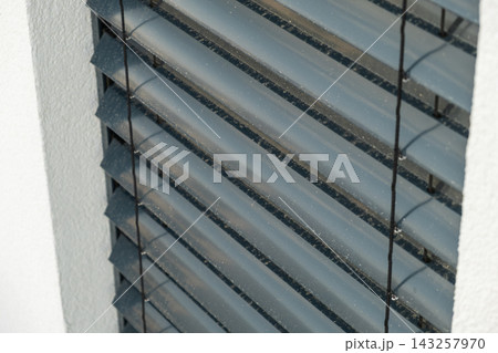 Adjustable aluminum blinds positioned within a window frame, offering customizable light filtration. The sleek design features horizontal slats with a muted gray finish, enhancing the modern aesthetic Adjustable aluminum blinds positioned within a window frame, offering customizable light filtration. The sleek design features horizontal slats with a muted gray finish, enhancing the modern aesthetic 143257970