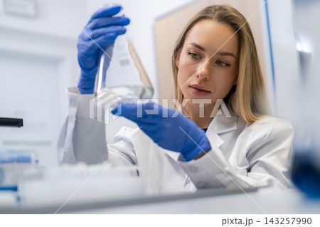 A professional researcher evaluates liquid samples within a clinical laboratory setting. A professional researcher evaluates liquid samples within a clinical laboratory setting. 143257990