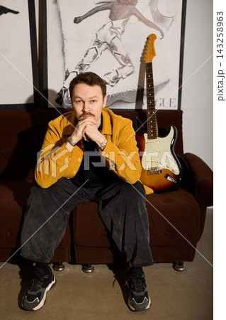 Performer standing confidently against illuminated textured backdrop Performer standing confidently against illuminated textured backdrop 143258963
