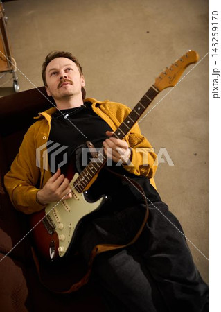 Musician embraces guitar. Indoor scene of tender musical affection 143259170
