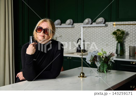 White woman stylist playfully toying with sunglasses and champagne 143259171