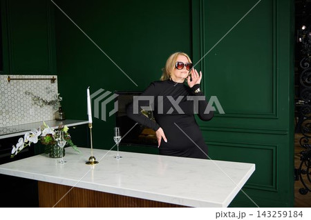 Confident female lifestyle personality in stylish green kitchen setting Confident female lifestyle personality in stylish green kitchen setting 143259184
