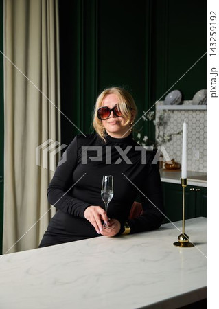 Novelist caucasian woman pausing with glass at kitchen island 143259192