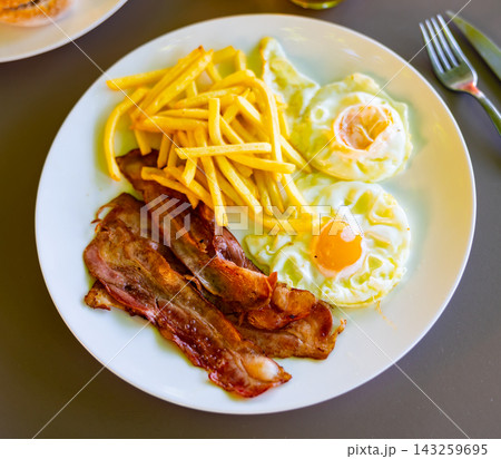 Homemade hearty breakfast - fried eggs with bacon and French fries Homemade hearty breakfast - fried eggs with bacon and French fries 143259695