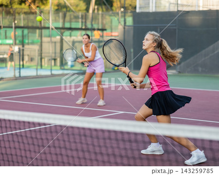 Sports active woman during friendly doubles couple match. Two women playing together tennis 143259785