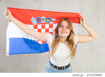 smiling girl in arms raised above head holds cloth of national flag of Croatia 143259862