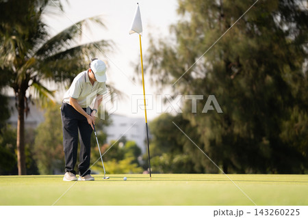 Male golfer kneeling on green reading putting line before stroke Male golfer kneeling on green reading putting line before stroke 143260225