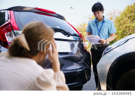 Insurance agent inspecting car damage with worried female driver 143260495