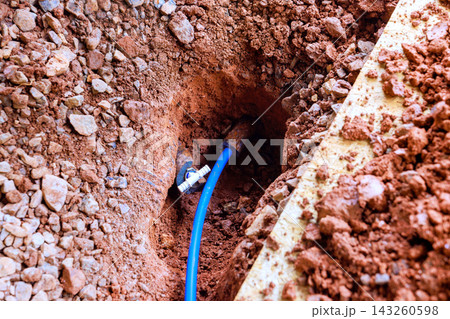 Workers are digging hole in ground to install blue pipe in construction area 143260598