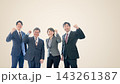 拳を握りやる気を見せる男女四人の会社員　ベージュ背景　右側に広い余白 143261387