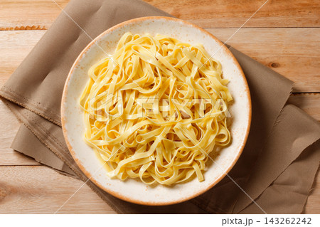 Cooked fresh fettuccine served on a rustic wooden plate with a cloth napkin. Cooked fresh fettuccine served on a rustic wooden plate with a cloth napkin. 143262242