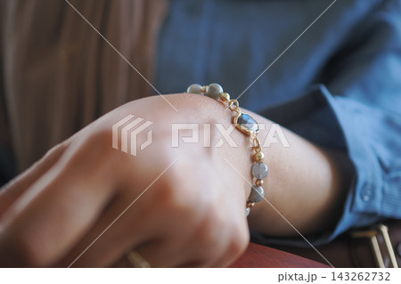 Woman wearing a bracelet while sitting at a table in a casual setting Woman wearing a bracelet while sitting at a table in a casual setting 143262732