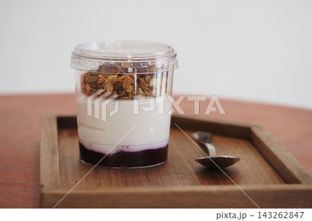 Dessert with yogurt, granola, and berry layer served on a wooden tray Dessert with yogurt, granola, and berry layer served on a wooden tray 143262847