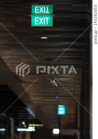 Exit signs hang in a corridor with dim light in a building Exit signs hang in a corridor with dim light in a building 143262853