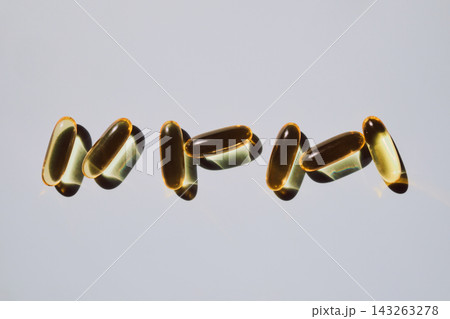 Yellow softgel capsules casting shadows on light background 143263278