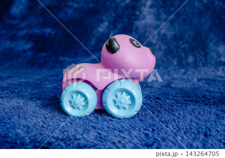 Bright pink toy car with blue wheels on a blue background Bright pink toy car with blue wheels on a blue background 143264705
