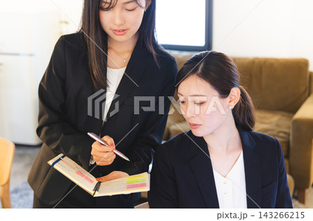 手帳を開き相談するビジネスウーマン 手帳を開き相談するビジネスウーマン 143266215