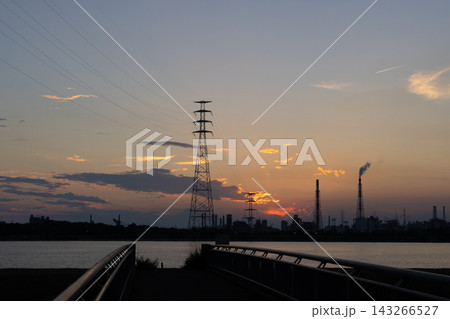 夕焼けの水辺に浮かぶ送電鉄塔と工場群のシルエット 143266527