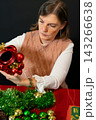 Woman Decorating Christmas Tree with Red Baubles 143266638