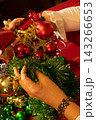 Hands Decorating Christmas Tree With Red and Gold Ornaments 143266653