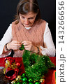 Woman Crafting a Festive Christmas Wreath with Green Tinsel 143266656