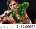Woman Decorating a Small Christmas Tree with Tinsel and Baubles 143266657