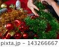 Hands Arranging Festive Christmas Tinsel and Ornaments 143266667