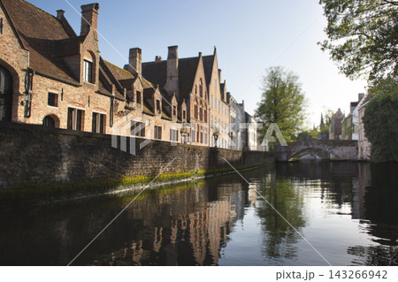 Scenic canal view with historic brick houses and an arched stone bridge in Bruges, Belgium 143266942
