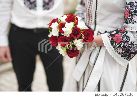 the bride and groom are holding hands with a bouquet of flowers and in traditional Ukrainian clothes 143267136