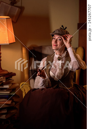 beautiful woman scientist in retro style smokes a pipe in the library reading books 143267707