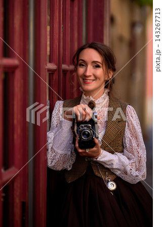beautiful woman scientist in retro style with a camera on the street of the old city 143267713