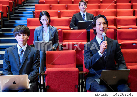 講演会の客席で積極的に質問をするスーツ姿の男性と参加者 講演会の客席で積極的に質問をするスーツ姿の男性と参加者 143268246
