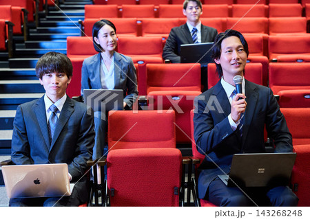 講演会の客席で積極的に質問をするスーツ姿の男性と参加者 講演会の客席で積極的に質問をするスーツ姿の男性と参加者 143268248