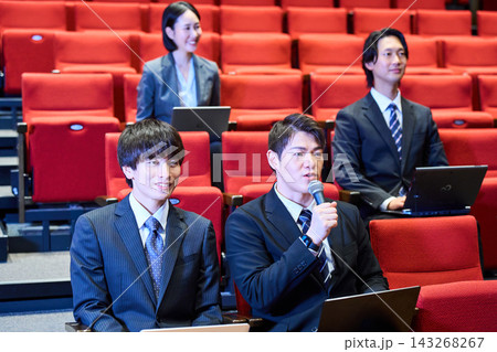 講演会の客席で積極的に質問をするスーツ姿の男性と参加者 講演会の客席で積極的に質問をするスーツ姿の男性と参加者 143268267